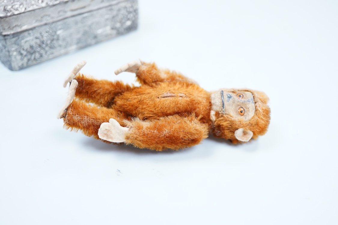 A German Schuco scent bottle monkey, with mohair body containing a glass bottle, together with a white metal Japanese style lid box decorated with a floral landscape and bird of prey to the lid